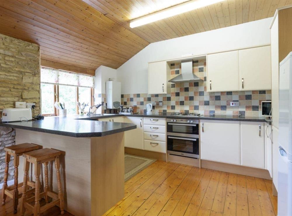 Well-equipped fitted kitchen with breakfast bar at The Mill House in Lea, near Ross-on-Wye, Herefordshire