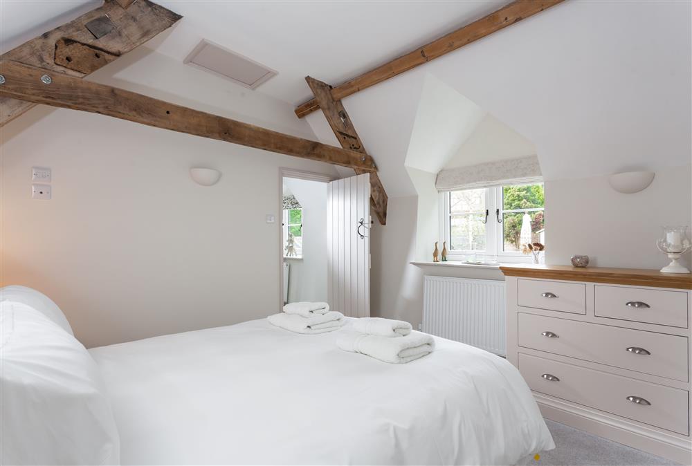 Bedroom two with a 5’ king-size bed and exposed beams at The Nook, Guiting Power