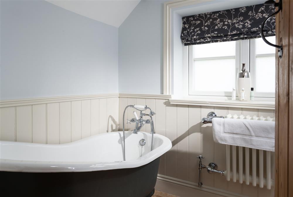 Ground floor family bathroom with a roll-top bath with overhead shower attachment at The Nook, Guiting Power