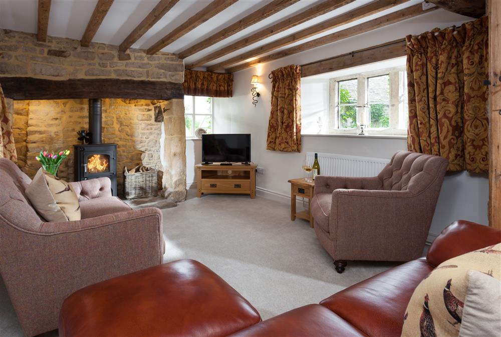 Sitting room with wood burning stove and exposed beams at The Nook, Guiting Power