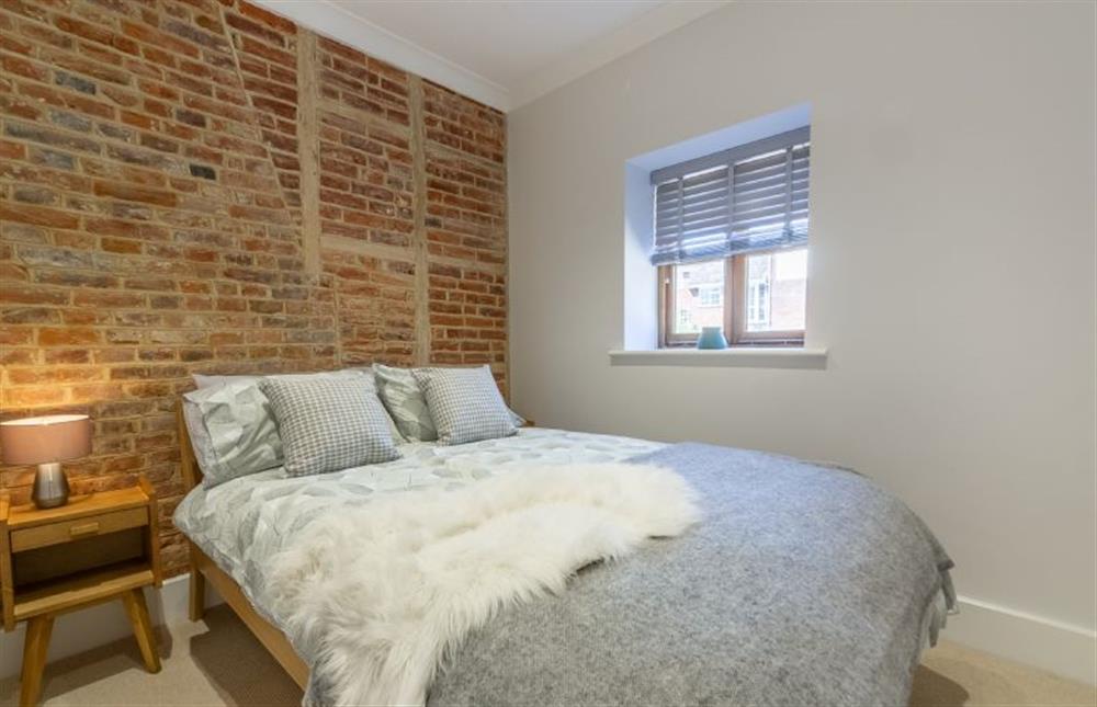 Ground floor: Bedroom two with a feature brick wall and a double bed at The Nurseries, Syderstone near Kings Lynn