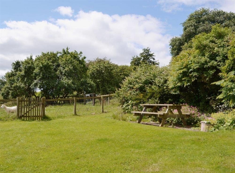 The large lawned garden has a picnic-style outdoor eating area at The Oast House in Whatmore, near Tenbury Wells, Shropshire