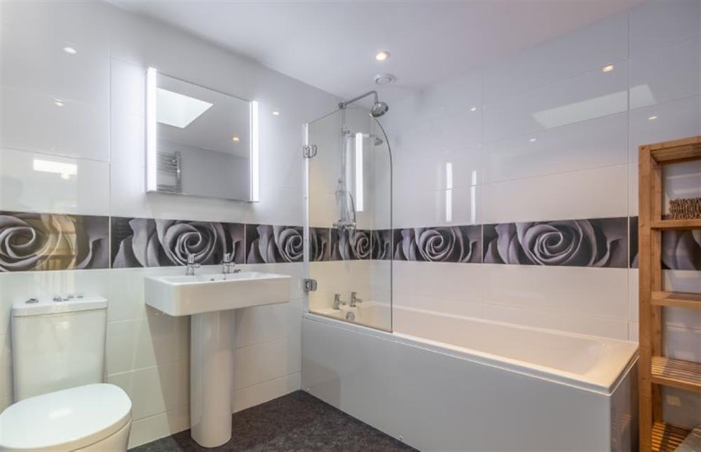 First floor: Family bathroom with a bath with shower over, wash basin and WC at The Old Barn, Weybourne near Holt