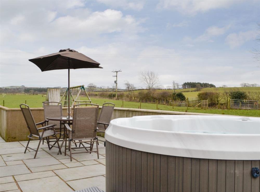 Enclosed patio area with hot tub at The Old Byre in Dearham, near Maryport, Cumbria