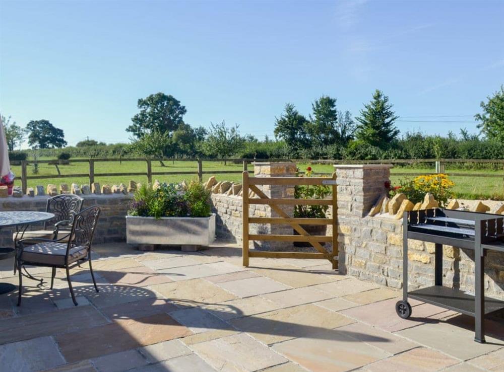 Enclosed garden with patio, sitting-out area and furniture at The Old Cowshed in Hornblotton, near Glastonbury, Somerset