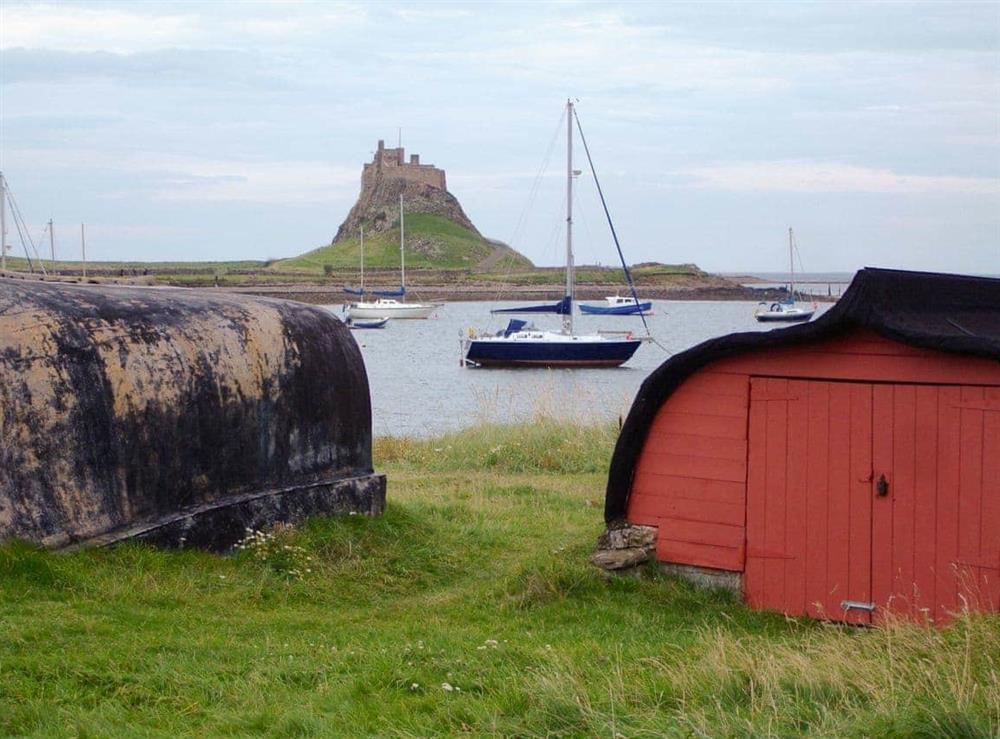 Lindisfarne Castle, harbour and upturned boats at The Old Granary in Holy Island, near Berwick-upon-Tweed, Northumberland