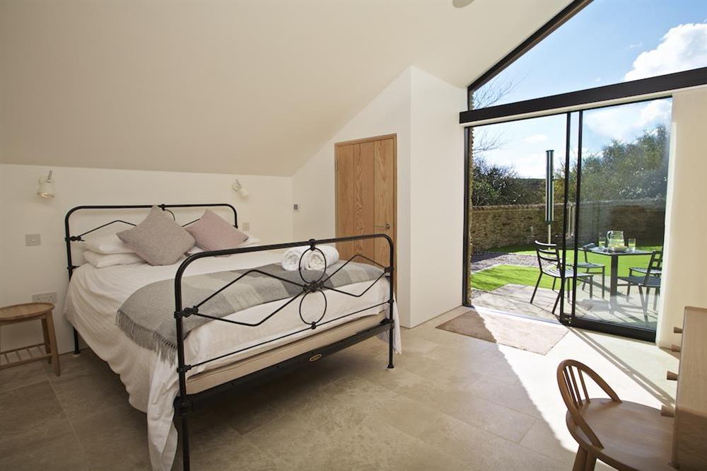 On the ground floor a master bedroom has a King-size bed with antique metal bedstead and sliding doors to the garden at The Old Milking Shed in , Bantham