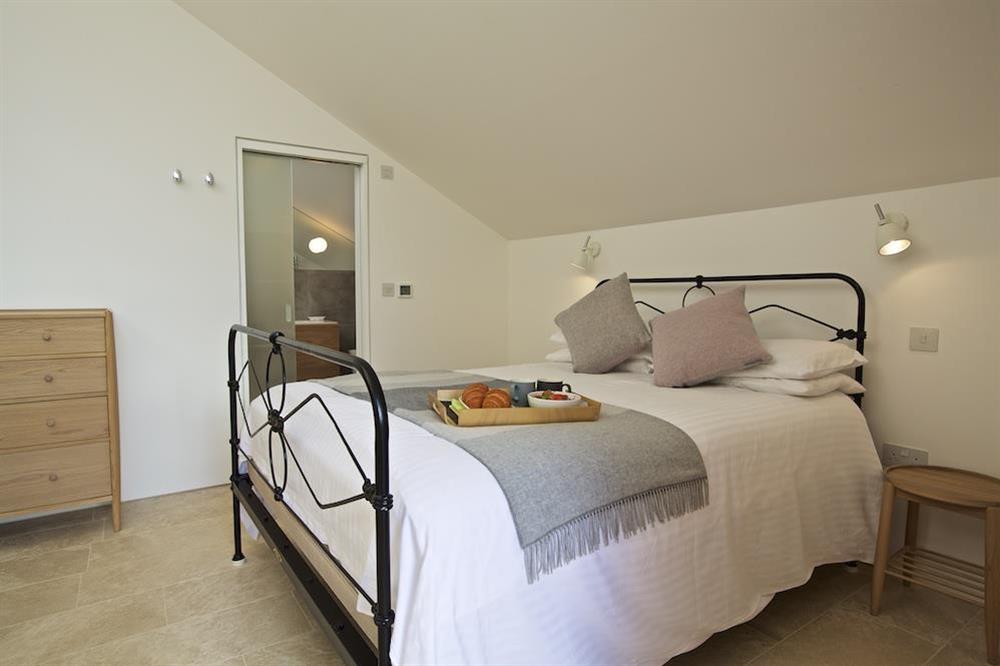 On the ground floor a master bedroom has a King-size bed with antique metal bedstead at The Old Milking Shed in , Bantham