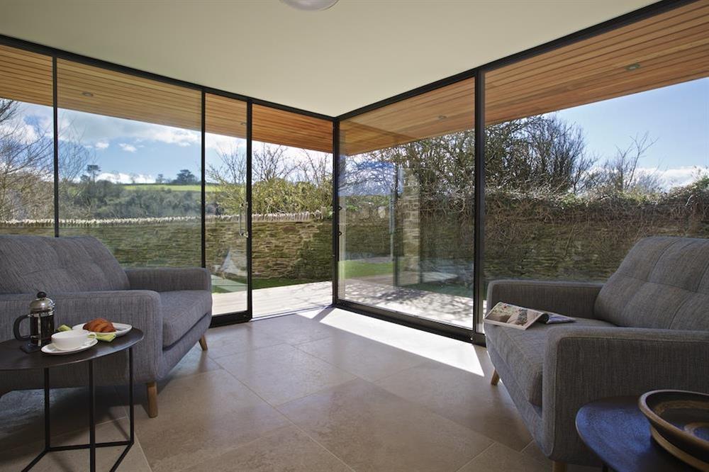 The sunroom with feature stone walls, sliding glass doors lead to the south facing garden at The Old Milking Shed in , Bantham
