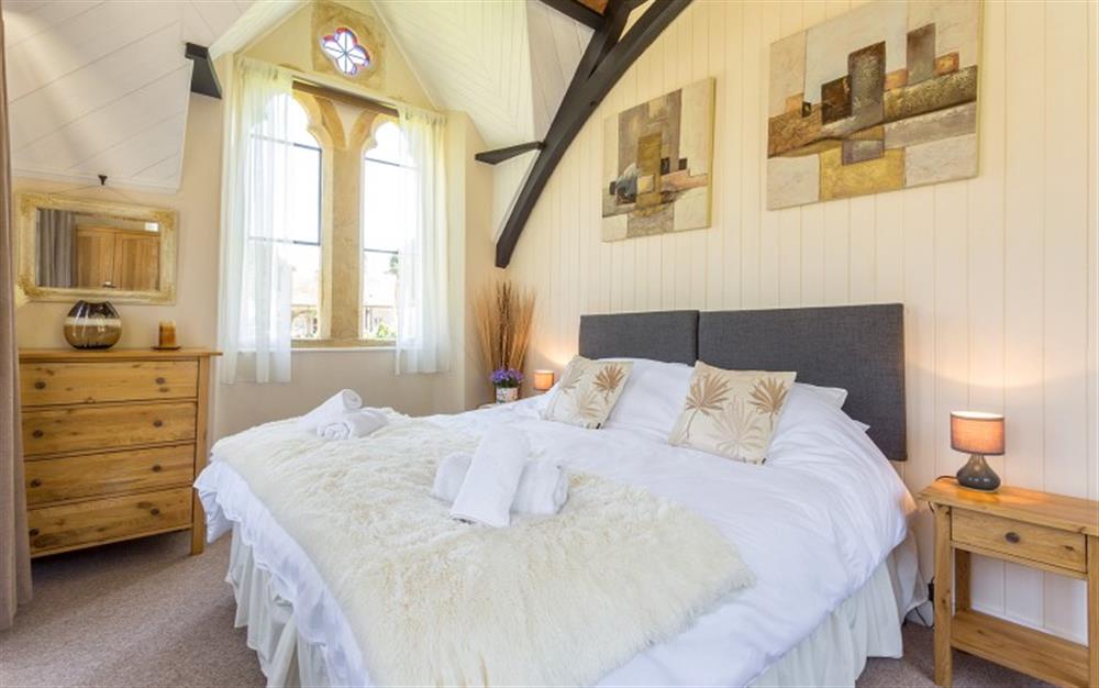 Bedroom 4 with impressive glass stained windows and views of the village at The Old School House in Powerstock