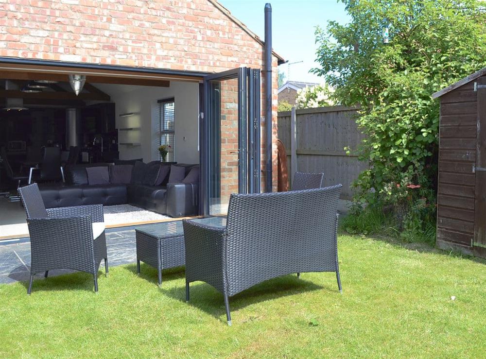 Bi-fold doors opening onto a flagged patio with seating area at The Old Stables in South Cave, near Beverley, Yorkshire, North Humberside