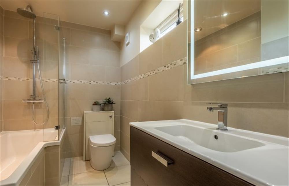 The Orangery: The bathroom has a bath with shower over, WC, basin and mirror (photo 2) at The Orangery, Snettisham near Kings Lynn