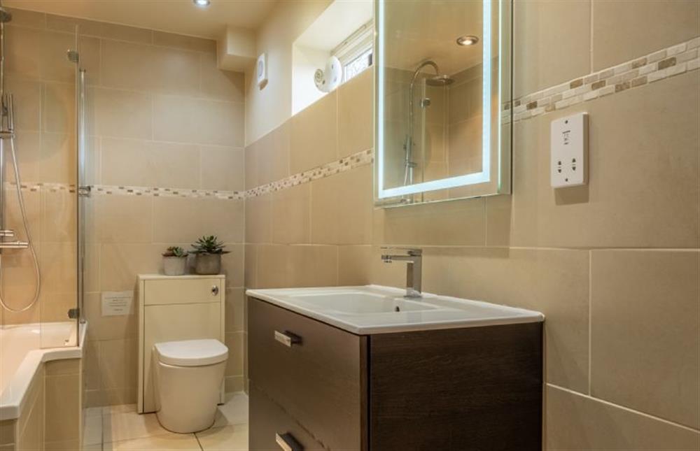 The Orangery: The bathroom has a bath with shower over, WC, basin and mirror at The Orangery, Snettisham near Kings Lynn