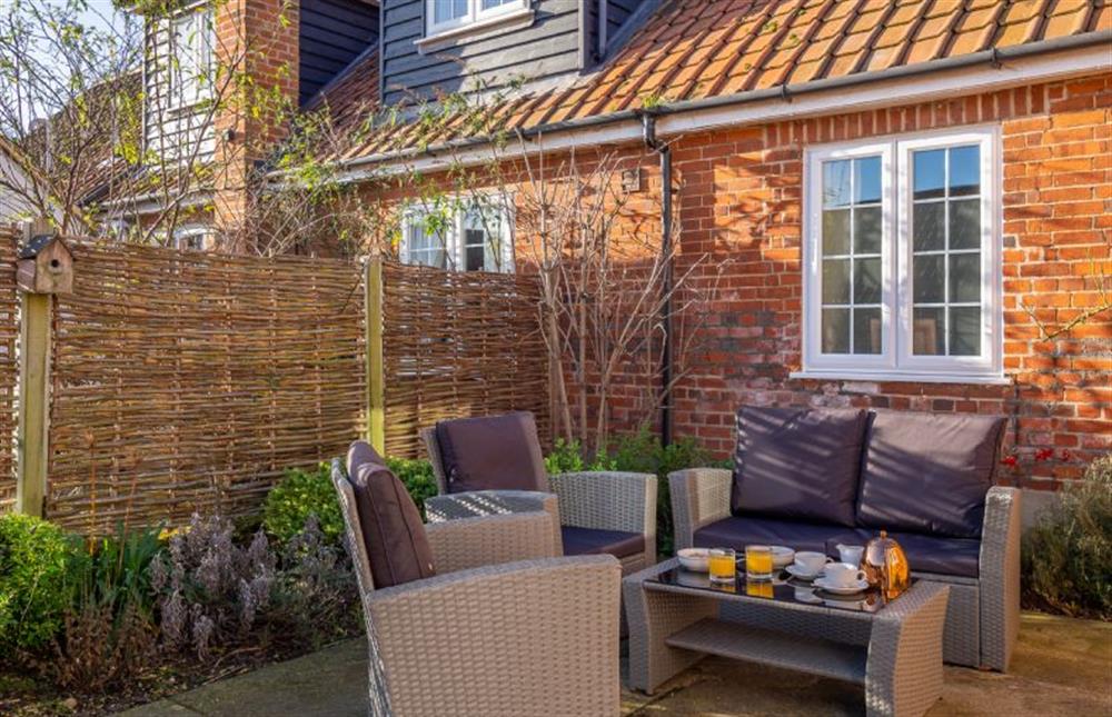 Small enclosed courtyard garden with rattan furniture at The Piggery, Colne Valley