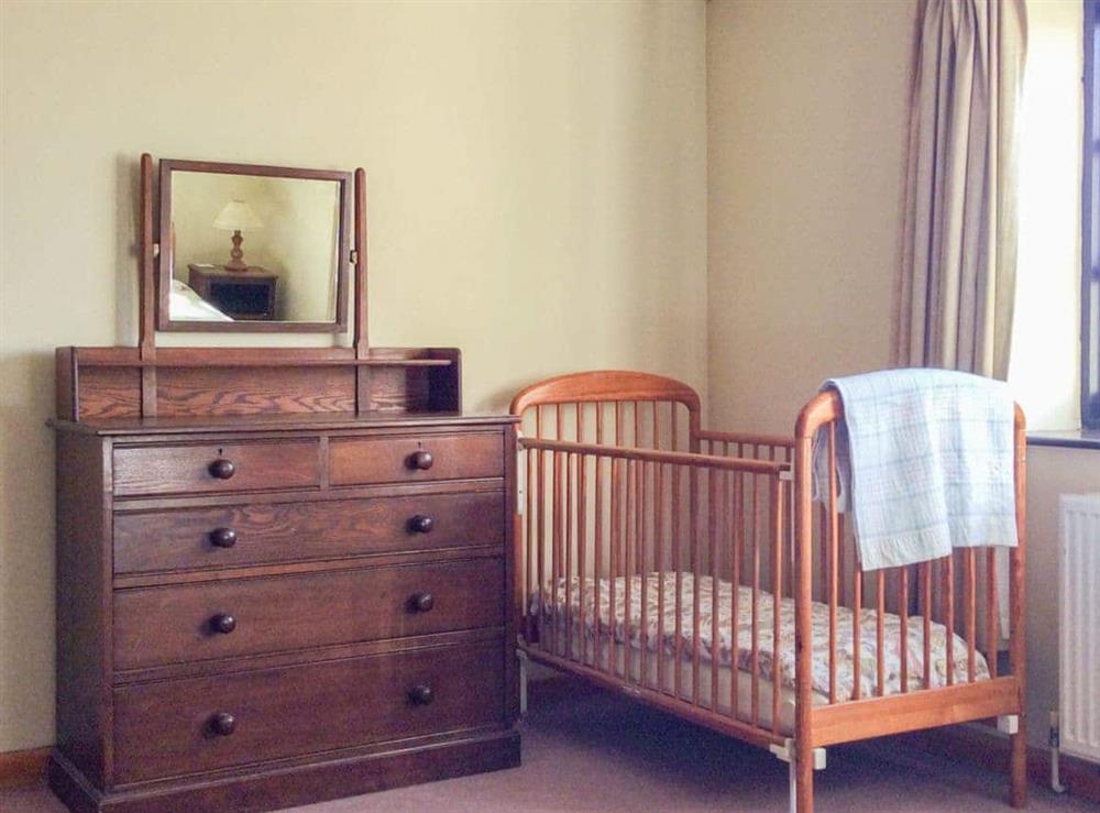 Twin bedroom with children’s cot at The Pump House in Hawkesbury Upton, Avon