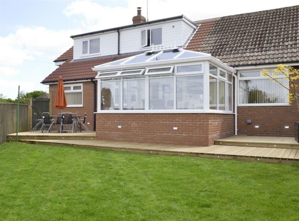 Rear of property with outdoor furniture and decked patios at The Retreat in Hunmanby, near Filey, North Yorkshire