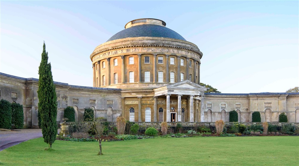 A long path lined with clipped yew balls leads the eye to a huge, round stone mansion at The Round House in Bury St Edmunds, Suffolk
