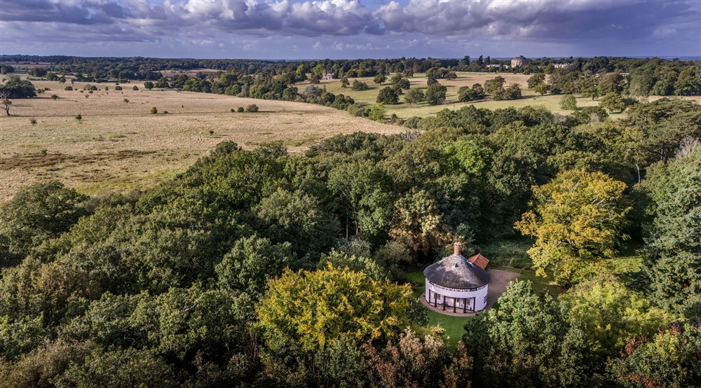 An aerial view of The Round House, with the Ickworth Estate House and parkland in the background, Suffolk at The Round House in Bury St Edmunds, Suffolk