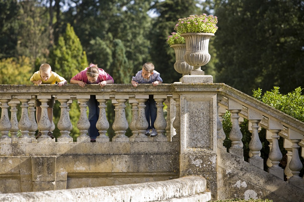 Children look down into the dry moat from the steps in the ITalianate Garden at The Round House in Bury St Edmunds, Suffolk