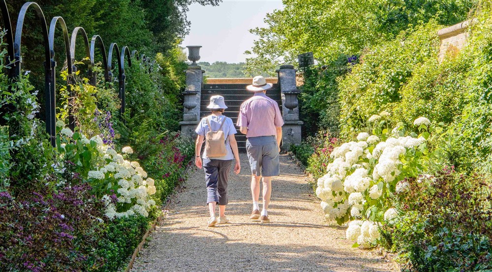 Couple walking down in the Victorian Border in Ickworrths Italianate garden at The Round House in Bury St Edmunds, Suffolk