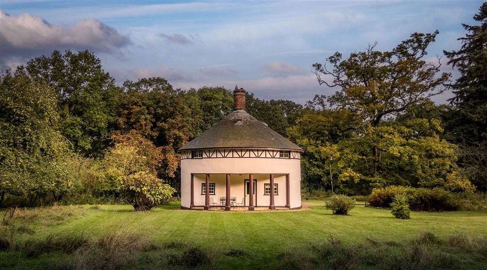 The exterior of The Round House, a rotunda cottage with a portico over a patio and large, lawned garden, surrounded by trees, Suffolk (photo 2) at The Round House in Bury St Edmunds, Suffolk