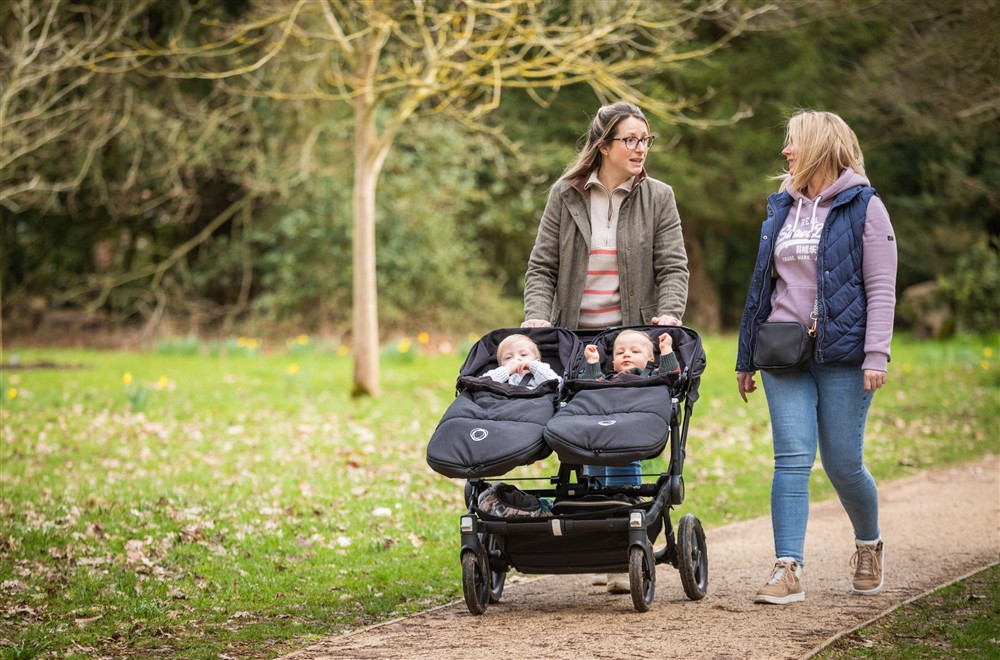 Two women walking down a path. One is pushing a stroller with two babies in. at The Round House in Bury St Edmunds, Suffolk