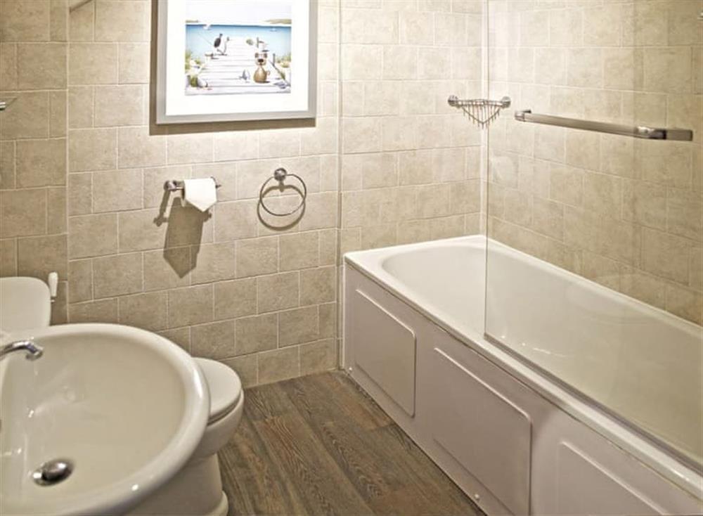 Stone tiled bathroom with a shower over the bath at The Salt Loft in Fowey, Cornwall
