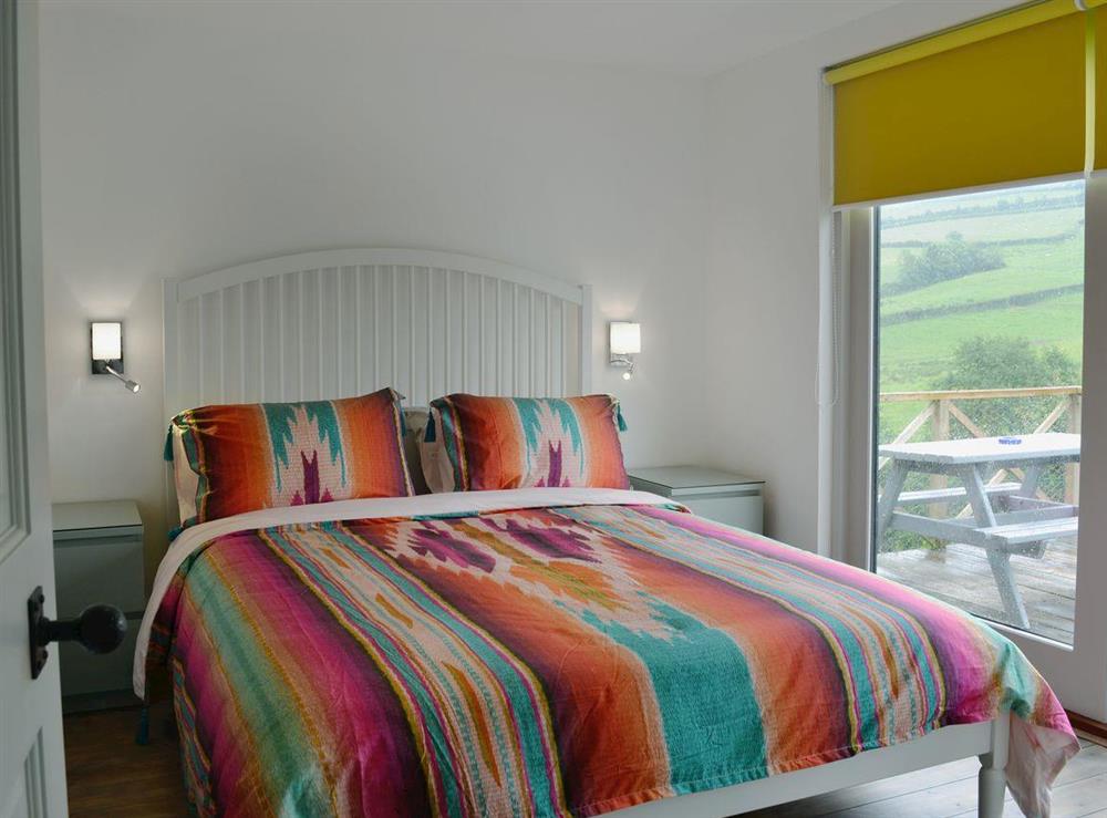 Comfortable double bedroom with doors leading to patio at The Shed with a View in Cadbury, near Crediton, Devon
