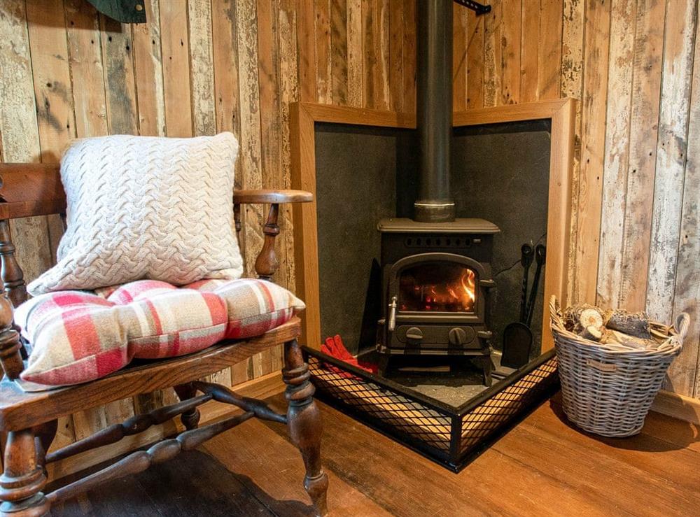 Comfortable seating area with wood burner at The Shepherds Hut at Gowan Bank Farm in Ings, near Windermere, Cumbria