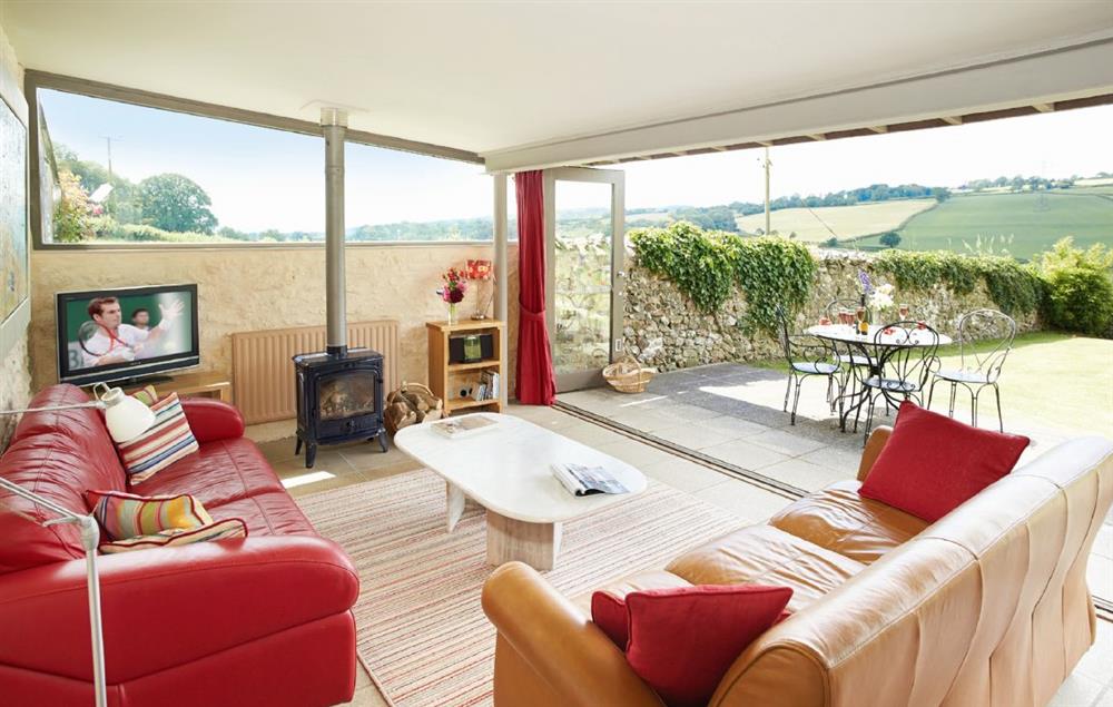 Sitting room with wood burning stove and large glazed doors opening onto the terrace with stunning views