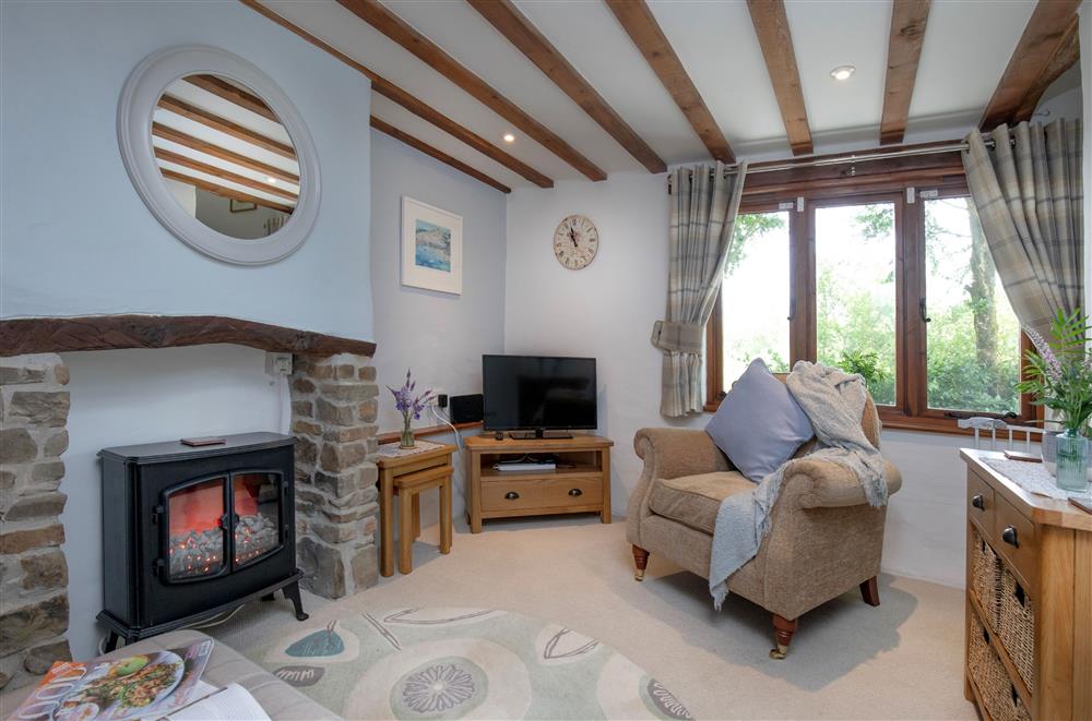 The sitting room with oak beams and an electric living flame fire