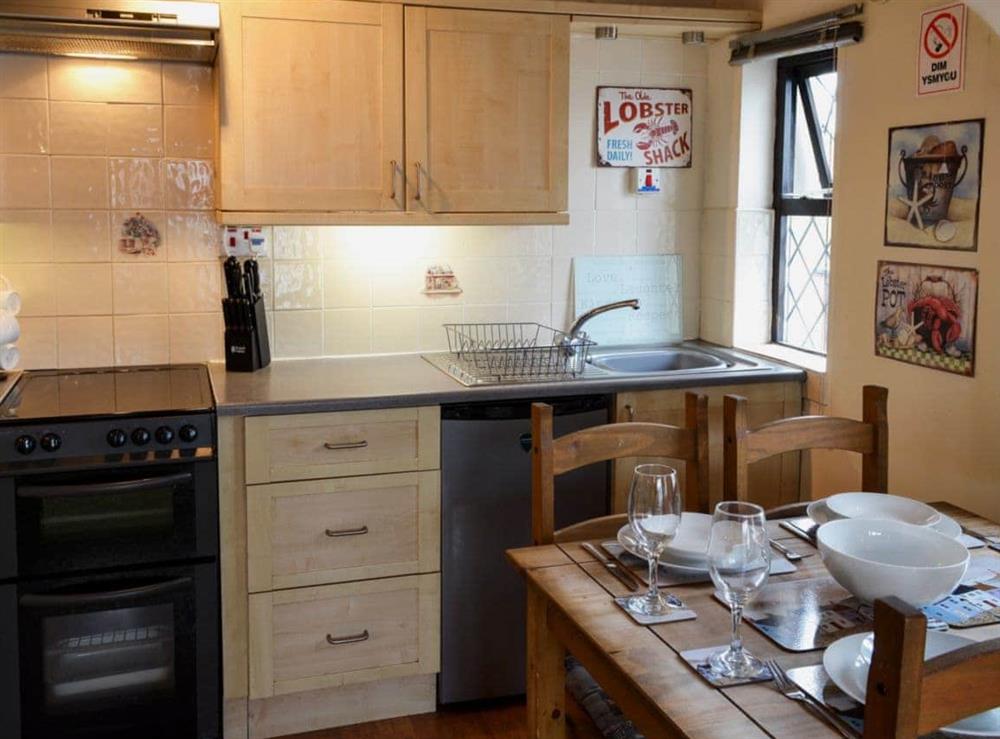 Galley style kitchen and dining area at The Studio Cottage in Cemaes, near Holyhead, Gwynedd