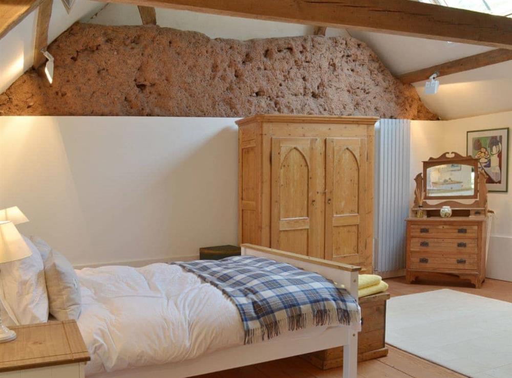 The beamed double bedroom retains some of the original barn construction at The Tithe Barn in Huxham, near Exeter, Devon