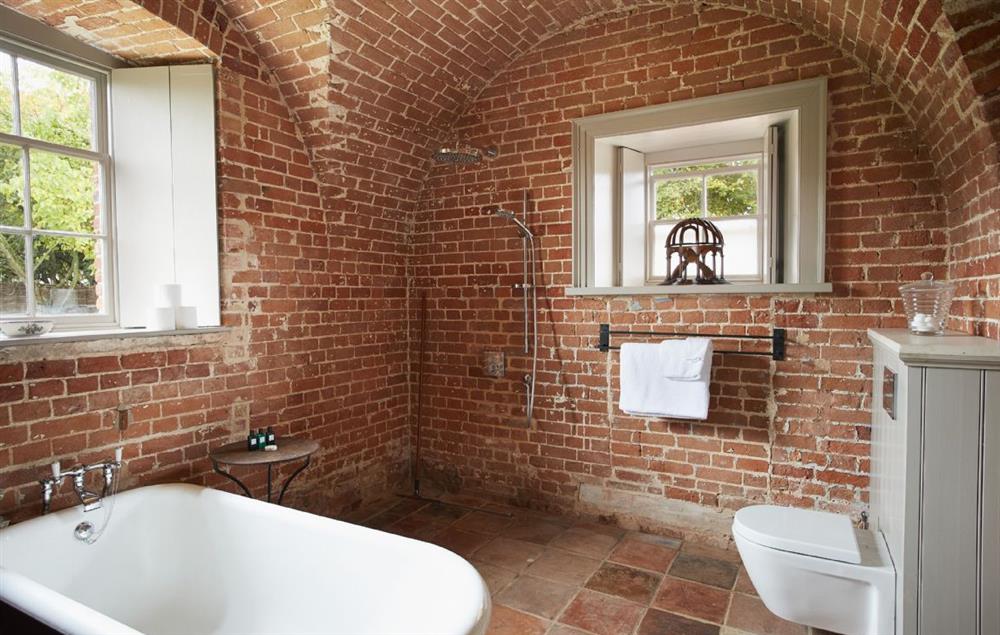 Vaulted brick bathroom with cast iron bath and Hans Grohe rain shower at The Treasury, Wolterton