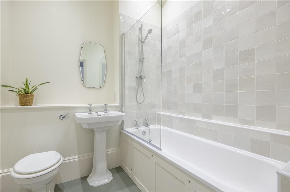 Bedroom three’s  en-suite bathroom with a bath and overhead shower at The Vicarage and Cottage, Great Limber