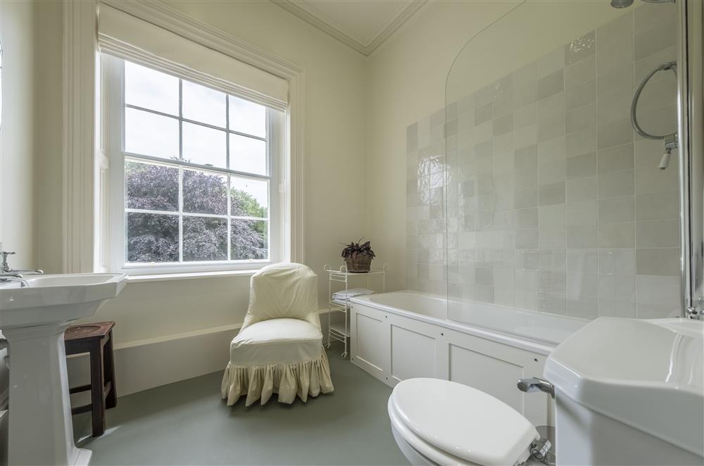 Bedroom two’s en-suite bathroom with a bath and overhead shower at The Vicarage and Cottage, Great Limber
