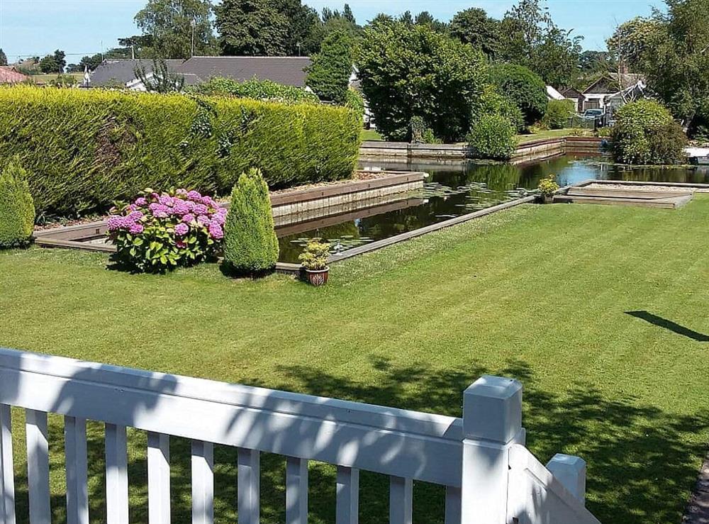 Lawned garden leading to the waters edge at The Willows in Wroxham, Norfolk