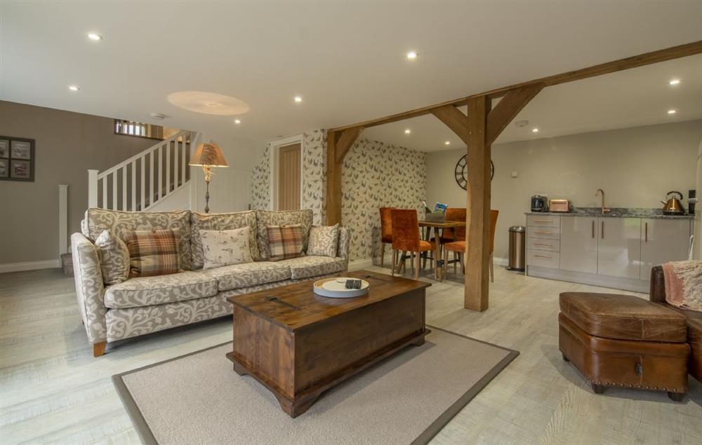 Open plan living area with dining table and chairs seating four guests at The Woodshed at Green Valley Farm, Ubbeston