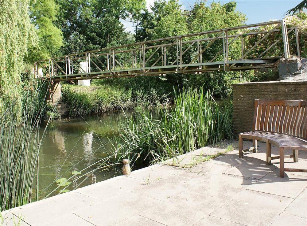 Riverside seating and bridge access to island at The Writing Room in Barford, near Stratford-upon-Avon, Warwickshire
