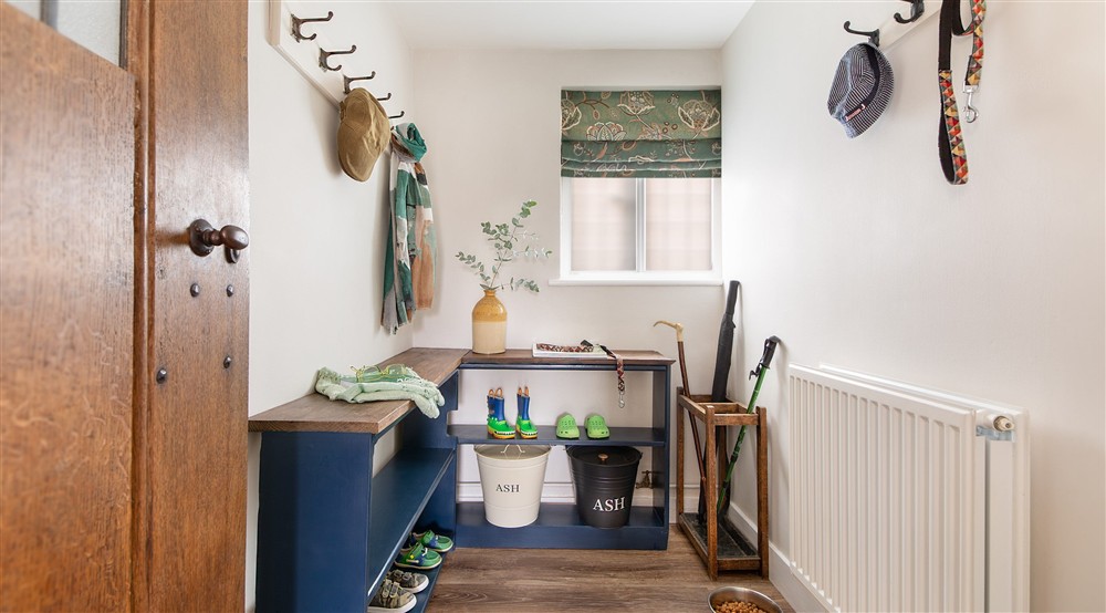The boot room with coat pegs, bench seating and shoe shelves at Thorington Hall in Stoke By Nayland, Suffolk