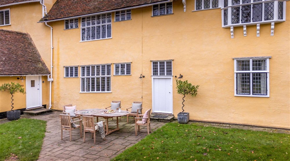 The northern terrace with patio and outdoor dining furniture and the main entrance to Thorington Hall on the left, Suffolk at Thorington Hall in Stoke By Nayland, Suffolk