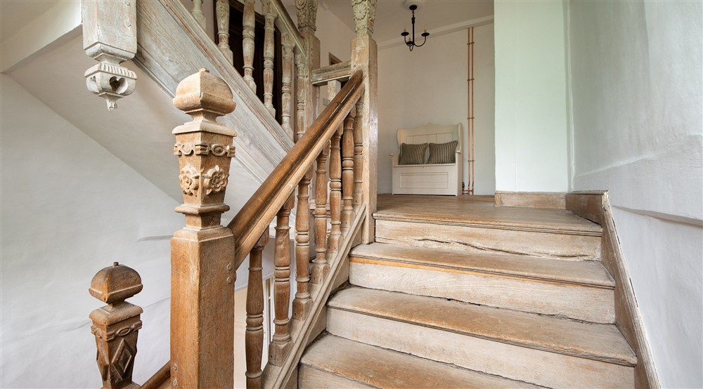The west staircase, decorated with Tudor roses, at Thorington Hall in Stoke By Nayland, Suffolk