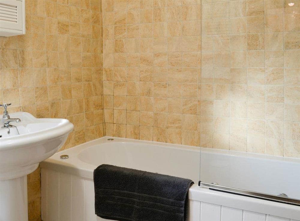 Tiled bathroom with shower over the bath at Thorpe Cottage in Masham, North Yorkshire
