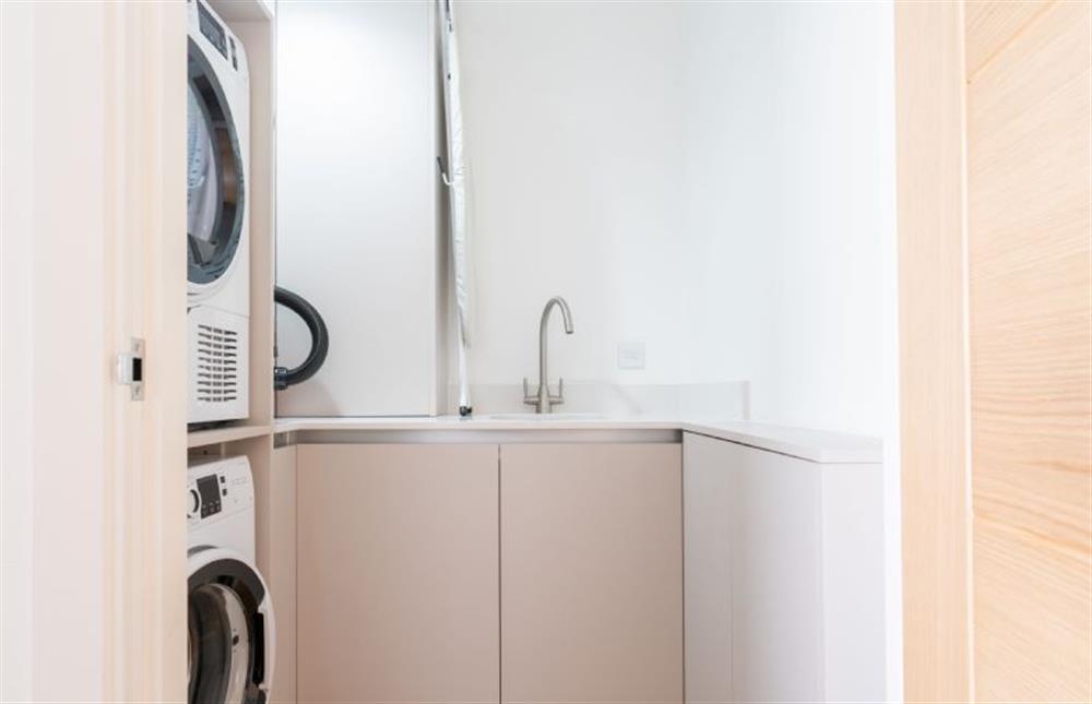 Utility room with a washing machine, tumble dryer and ironing facilities at Tidelines, Newquay