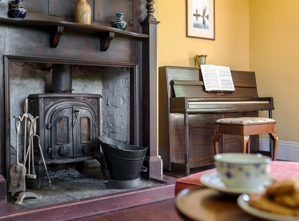 Wood burner and piano in second living room at Tilney Hall in Kings Lynn, Norfolk