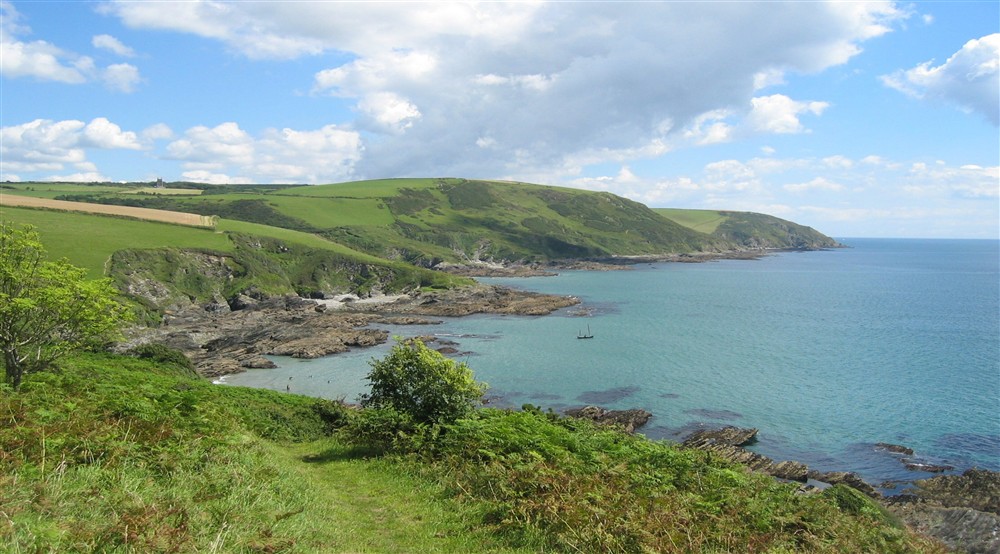 View of bay with clear blue sea and grassy headland beyond at Tippett's in Lanteglos-by-fowey, Cornwall