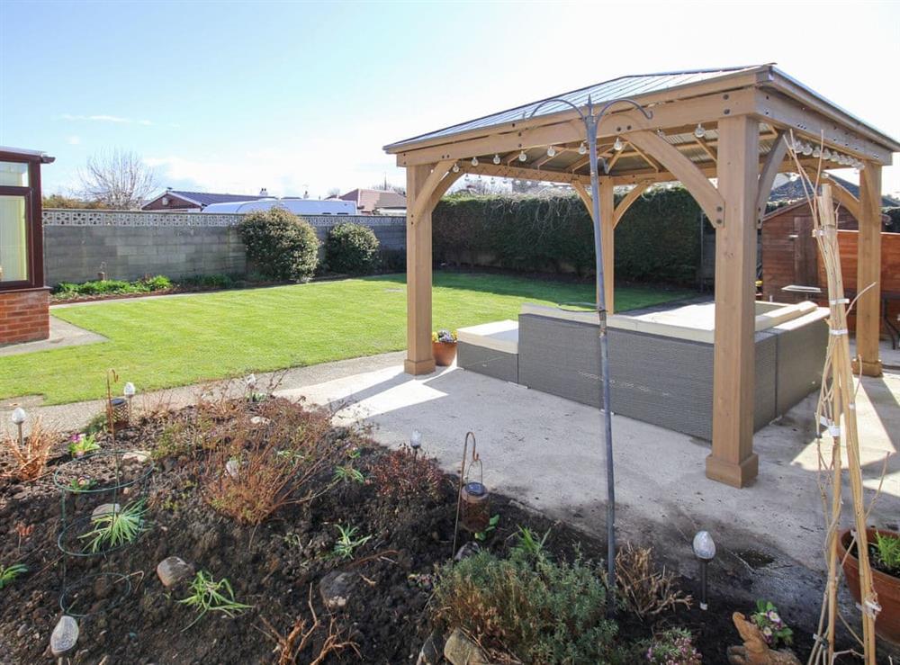 Rear garden with covered patio area and lawn at Tir Nani Ogg in Towyn, near Rhyl, Conwy