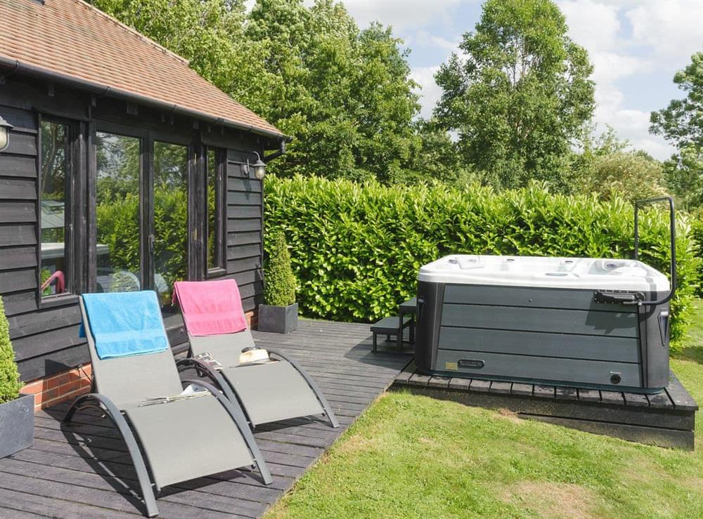 Decked patio with hot tub and sun loungers at Toad Hall Cottage in White Colne, near Colchester, Essex