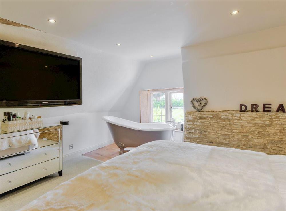 Romantic double bedroom featuring a rolltop bath at Tom Cottage in Wing, near Oakham, Leicestershire
