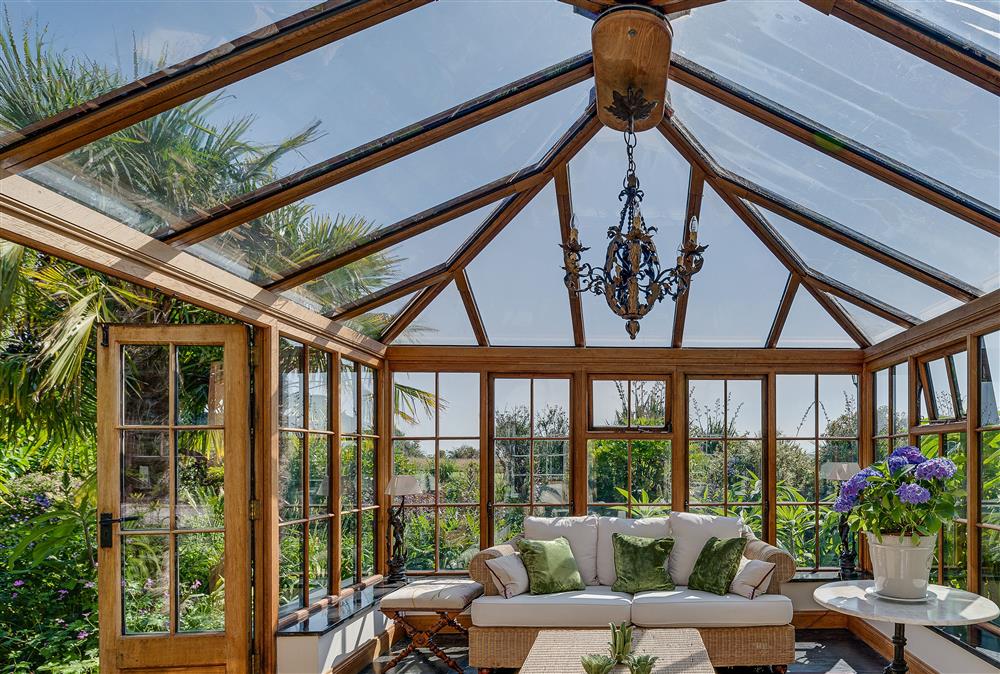 Conservatory with seating and doors opening onto the patio and garden at Tregadjack Farmhouse, Tregathenan